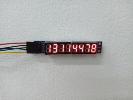 A seven-segment LED display module mounted on a wall, showing the numbers “13114478” in red. The module is connected by five colored wires to a controller labeled VCC, GND, DIN, CS, and CLK. 